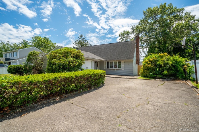 View of front facade with an attached garage, a chimney, and asphalt driveway