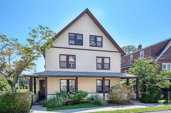 View of front of house featuring covered porch and a shingled roof
