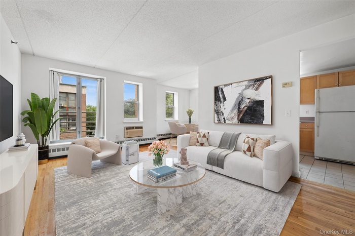 Living room with a textured ceiling, light wood-style flooring, and baseboard heating