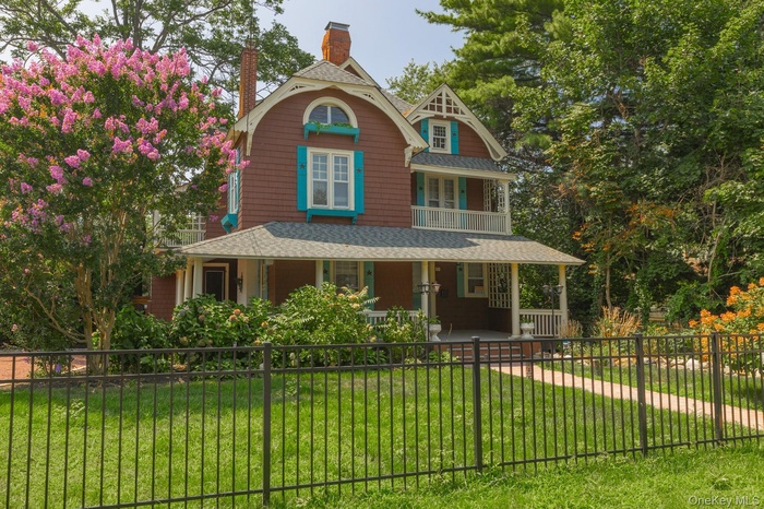 Victorian home with a fenced front yard, a porch, a chimney, and roof with shingles