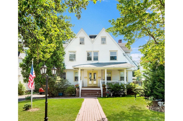 Shingle-style home with a porch, a front lawn, a shingled roof, a chimney, and french doors