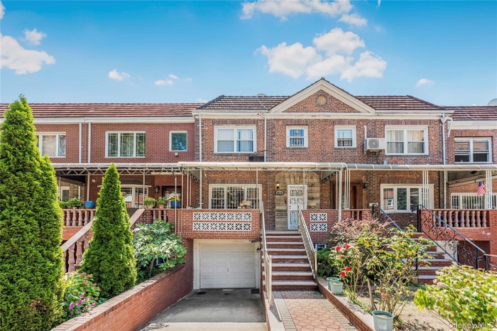 Traditional-style house with an attached garage, concrete driveway, stairway, and brick siding