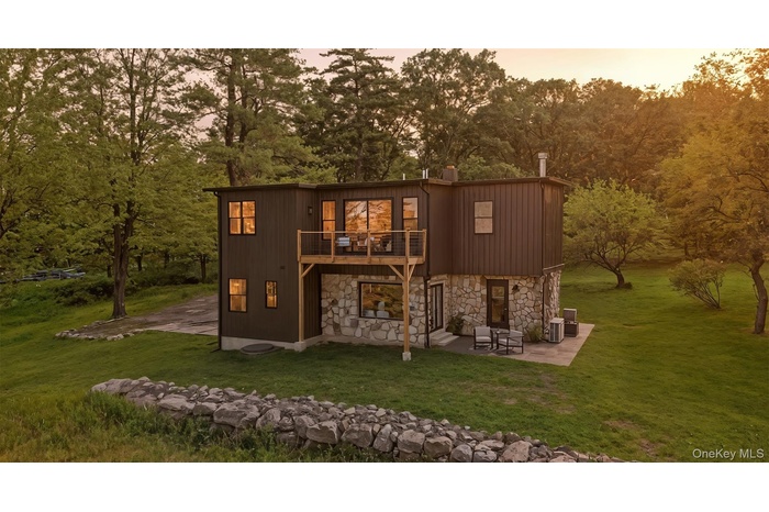 Back of house with a patio area, stone siding, and a yard