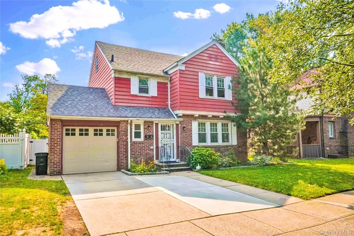 View of front of home with roof with shingles, concrete driveway, brick siding, and a garage