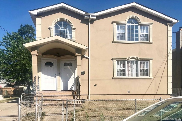 View of front facade with stucco siding, a gate, and a fenced front yard