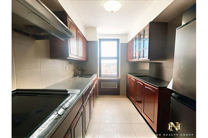 Kitchen with black electric cooktop, range hood, backsplash, dark countertops, and freestanding refrigerator