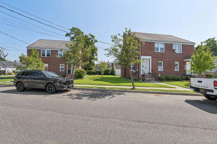 Colonial house with a front lawn, brick siding, and a residential view