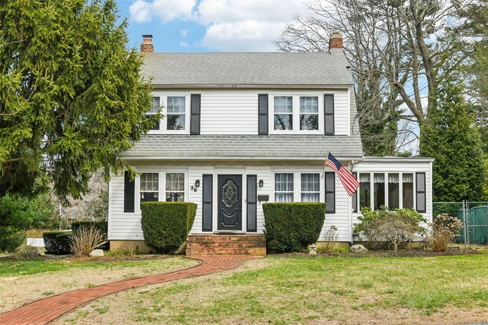 View of front of house with a front yard, fence, roof with shingles, and a chimney