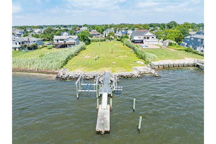Dock area featuring boat lift, a water view, a lawn, and a residential view