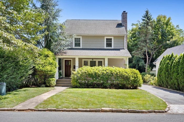 American foursquare style home featuring a porch, a front yard, roof with shingles, and a chimney