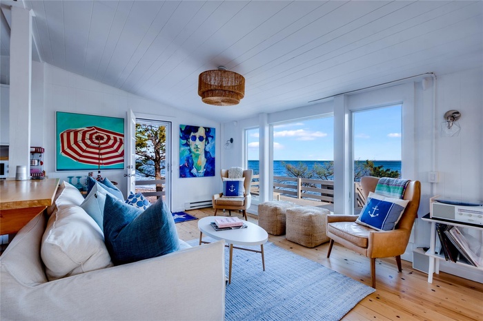 Living area with a water view, a healthy amount of sunlight, a baseboard radiator, and vaulted ceiling