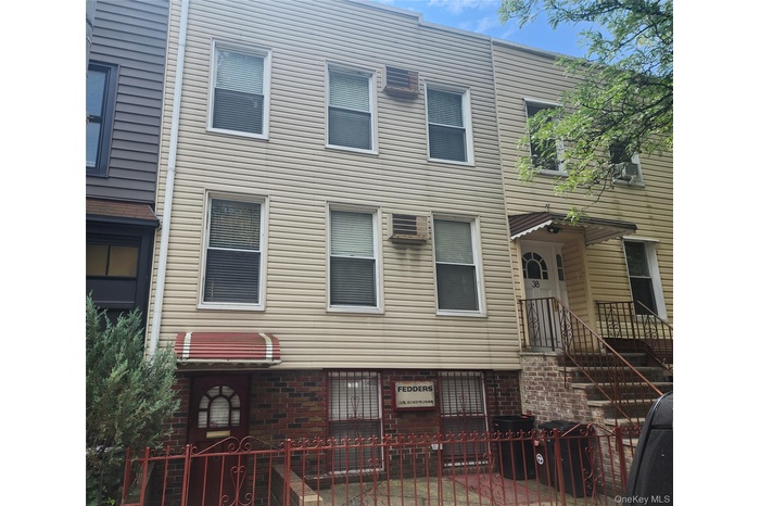 Back of property featuring a fenced front yard and a wall mounted AC