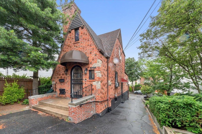 Tudor home with brick siding, a shingled roof, and a chimney
