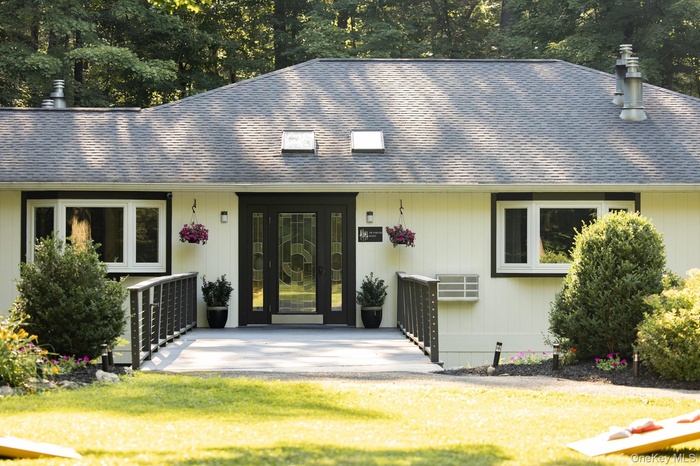 View of front of property featuring a shingled roof and a front lawn