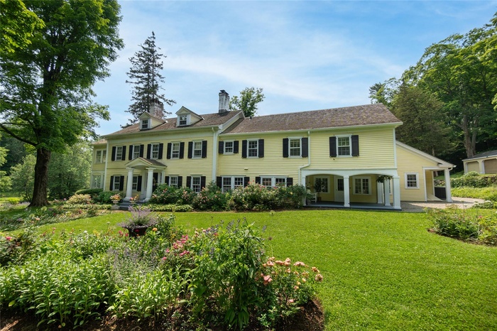 View of front of house with a chimney, a front yard, and a patio