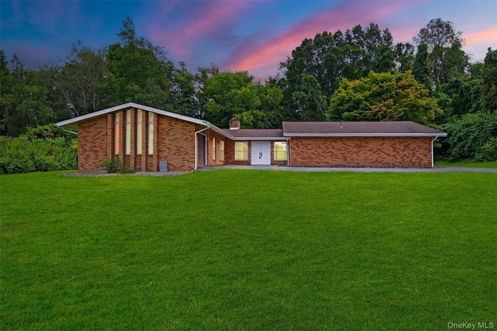Mid-century inspired home featuring brick siding, a yard, and a chimney