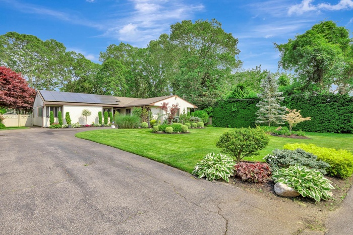 View of front of house featuring solar panels and asphalt driveway