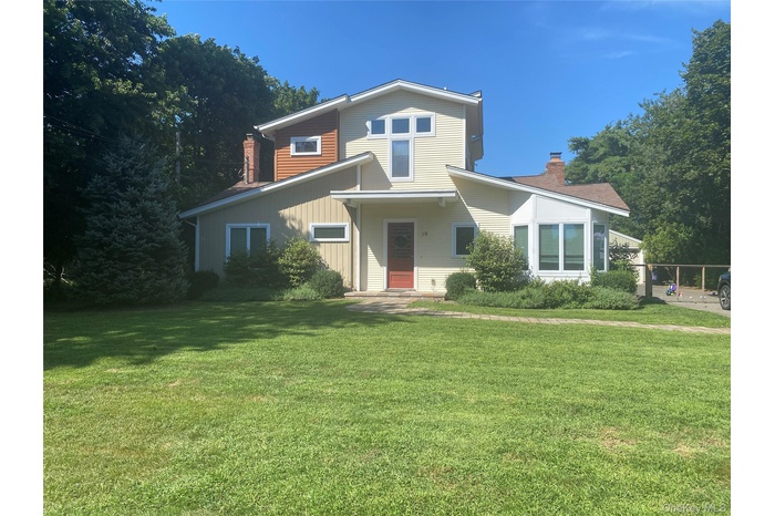 View of front facade with a chimney, a front lawn, and board and batten siding