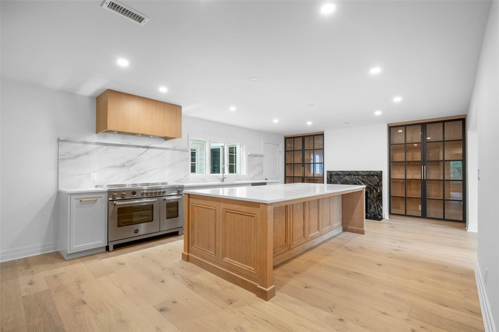 Kitchen with range with two ovens, tasteful backsplash, recessed lighting, light countertops, and light wood-style floors