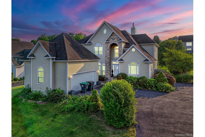 Traditional-style house with a shingled roof, an attached garage, asphalt driveway, and a chimney