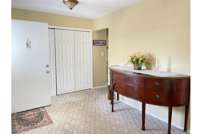 Foyer featuring light colored carpet, wall to wall coat closet