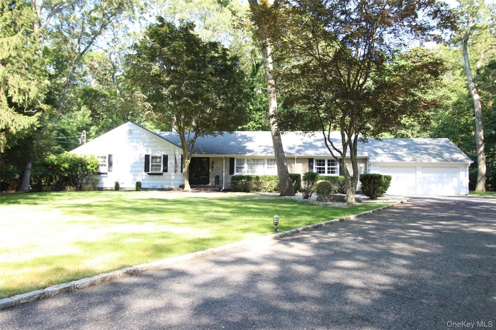 Single story home with asphalt driveway, an attached garage, and a front yard
