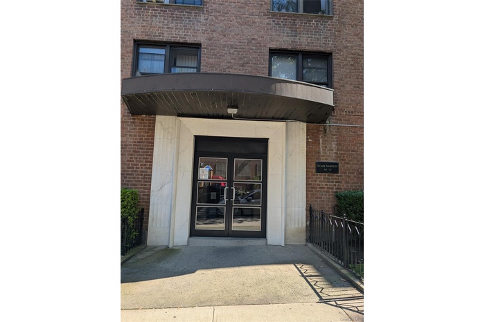 View of exterior entry featuring french doors, brick siding, and a balcony