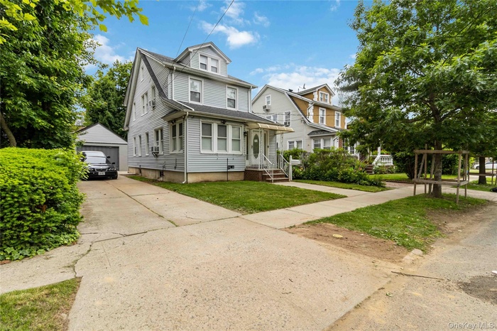Traditional style home with a garage, a front yard, and an outbuilding