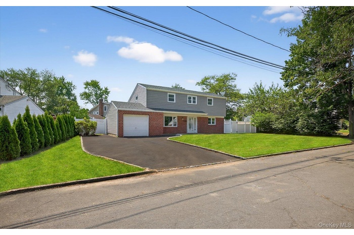 Colonial home featuring asphalt driveway, brick siding, and an attached garage