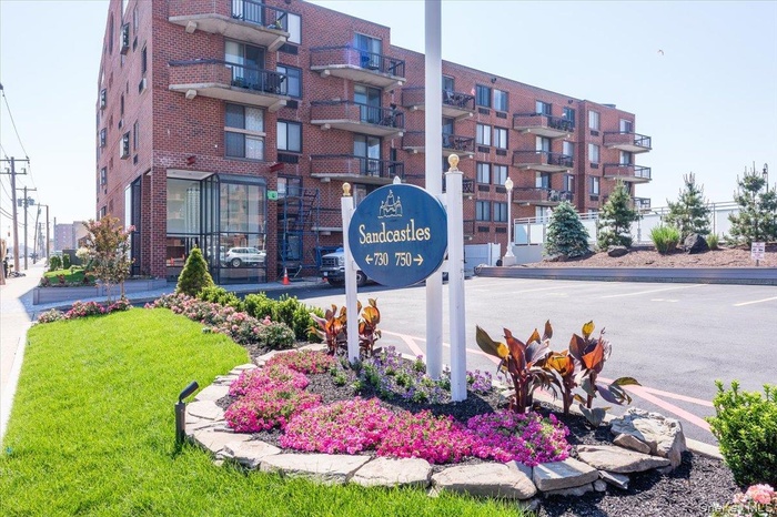 Community sign featuring uncovered parking and a lawn