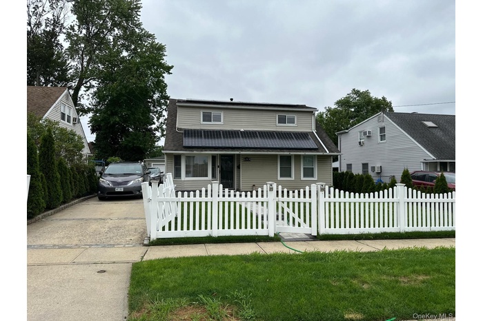 View of front facade featuring a fenced front yard, driveway, a gate, and roof with shingles