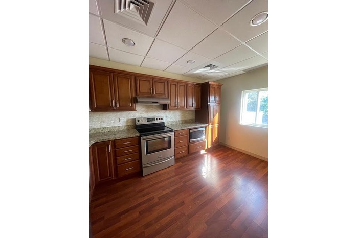Kitchen featuring stainless steel appliances, baseboards, under cabinet range hood, dark wood-type flooring, and backsplash