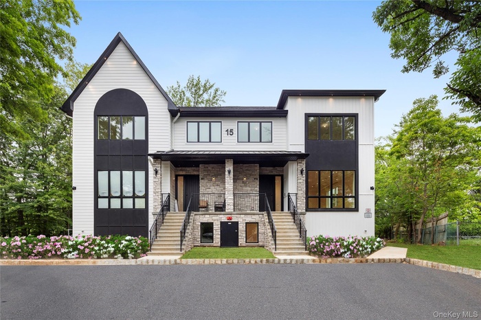 View of front facade with a porch, stone siding, a standing seam roof, stairway, and a metal roof