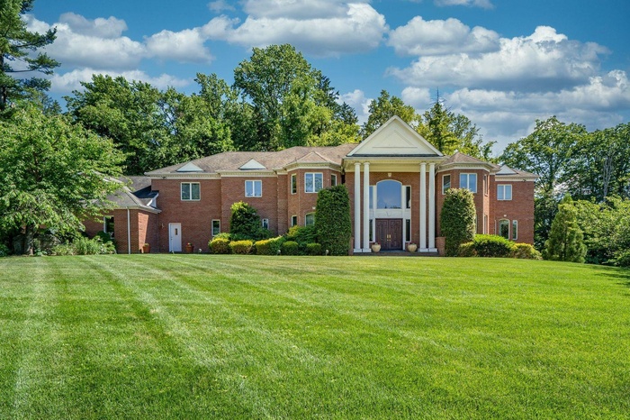 Neoclassical home with a front lawn and brick siding