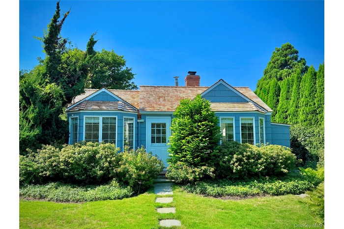 View of front of property featuring a chimney and a front lawn