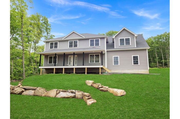View of front facade featuring a front lawn and a shingled roof