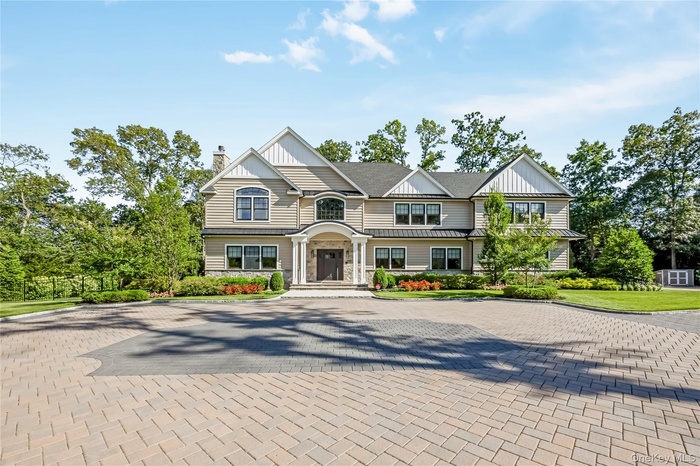 Craftsman-style house with a chimney, board and batten siding, and decorative driveway
