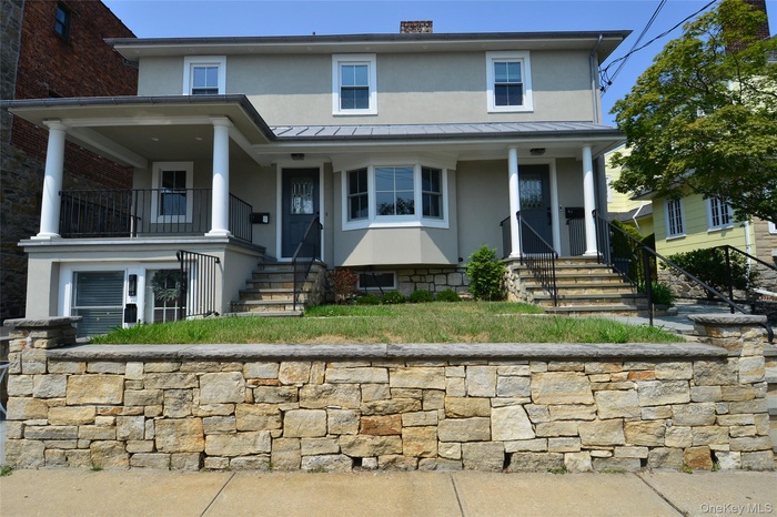 View of front of house with stucco siding, a standing seam roof, and a chimney