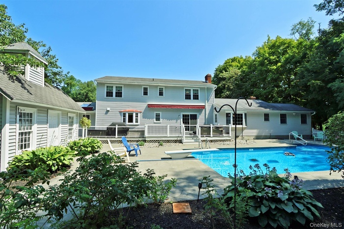 Backyard pool with a diving board, a patio area, and a deck