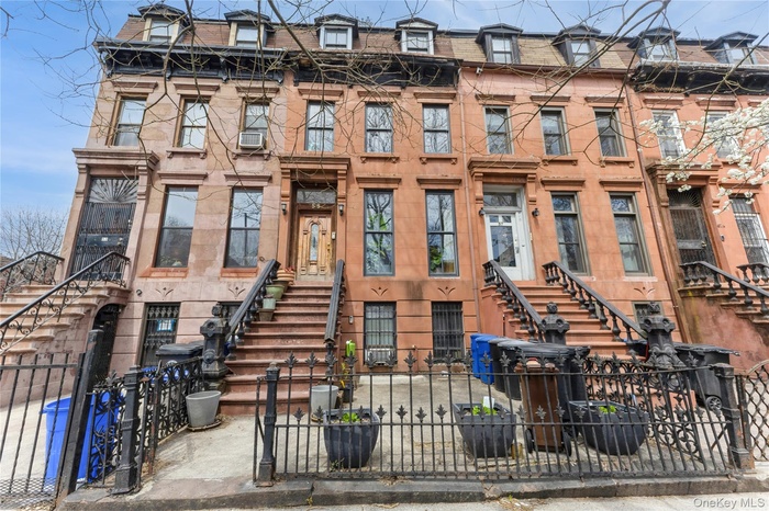 View of front of house with a fenced front yard and mansard roof