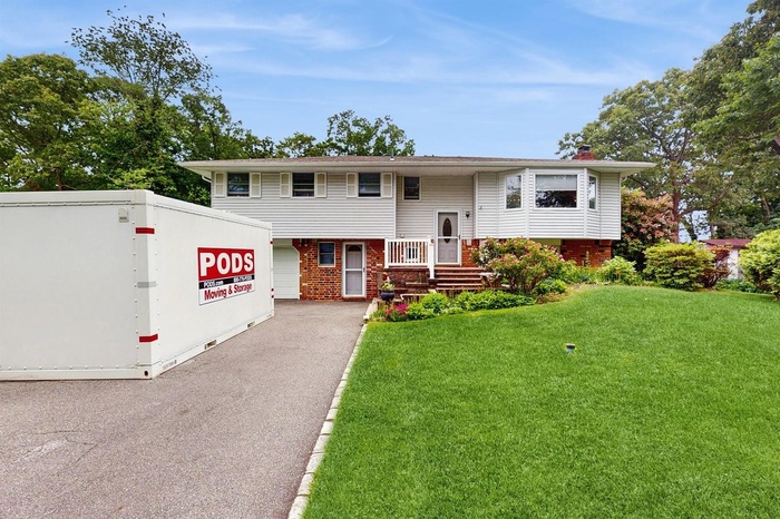 Bi-level home featuring brick & vinyl siding, a front lawn, and a chimney