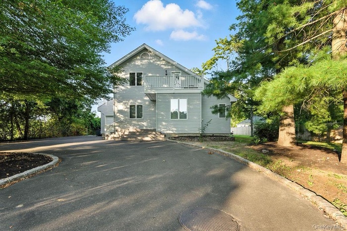 View of front of house with driveway, a balcony, and a garage