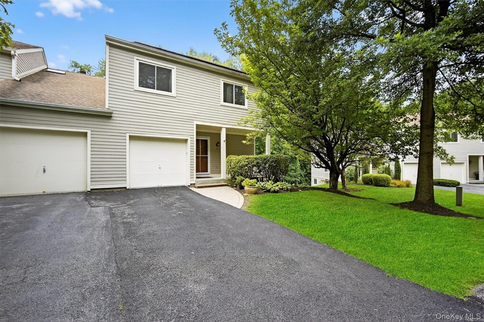Traditional home with asphalt driveway, a front lawn, and a shingled roof