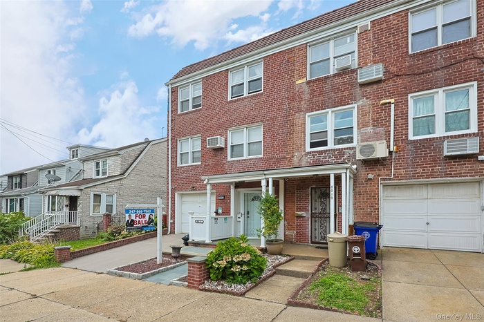 Traditional home featuring brick siding, driveway, a garage, a residential view, and a wall mounted air conditioner
