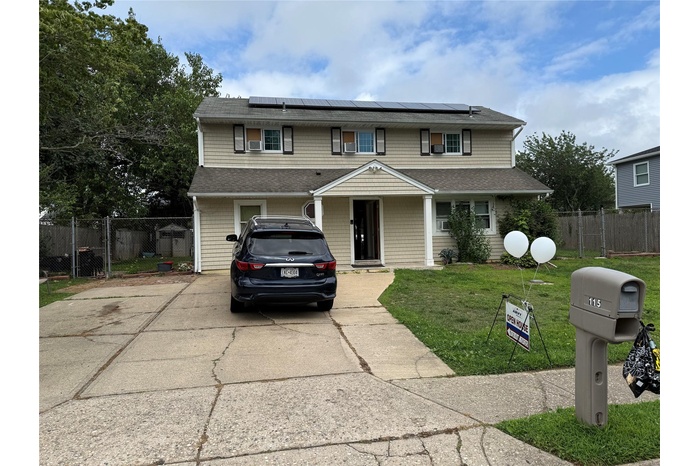 Traditional home featuring roof mounted solar panels, driveway, and a gate