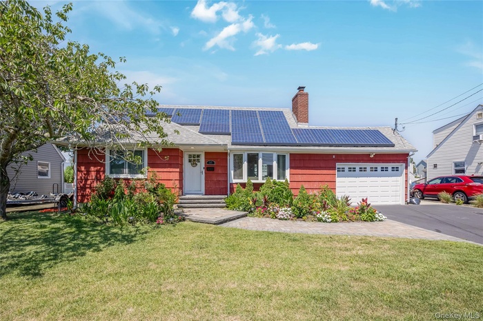 Ranch-style home featuring an attached garage, solar panels, and a front yard