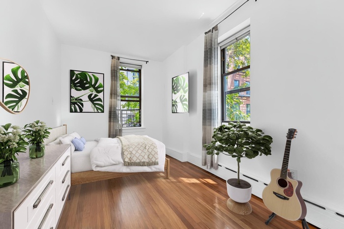 Bedroom with wood finished floors, baseboard heating, and baseboards