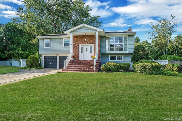 Raised ranch with concrete driveway, an attached garage, and a chimney