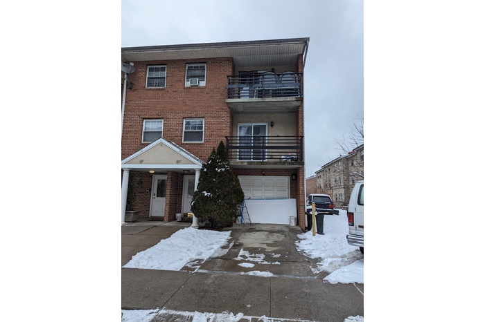 View of front of home featuring a garage and a balcony