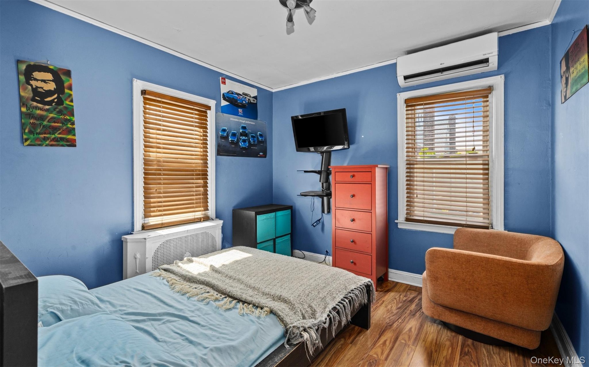 Bedroom featuring wood finished floors, a wall unit AC, radiator heating unit, and ornamental molding